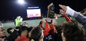 Men's soccer celebrates after the game with the trophy