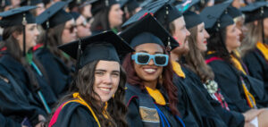 Two graduates smile at the camera during commencement in Spangler Stadium