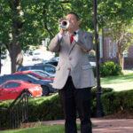 an officer salutes while the trumpeter plays taps
