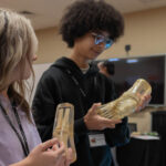 Two students hold skeleton models