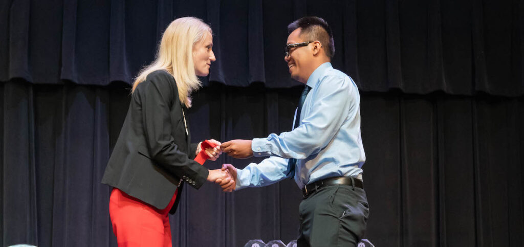 Nicole Waters shakes hand of new visiting instructor Scott Vayakone.