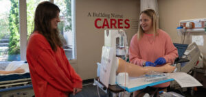 Two nursing students practice on a mannequin in the nursing lab