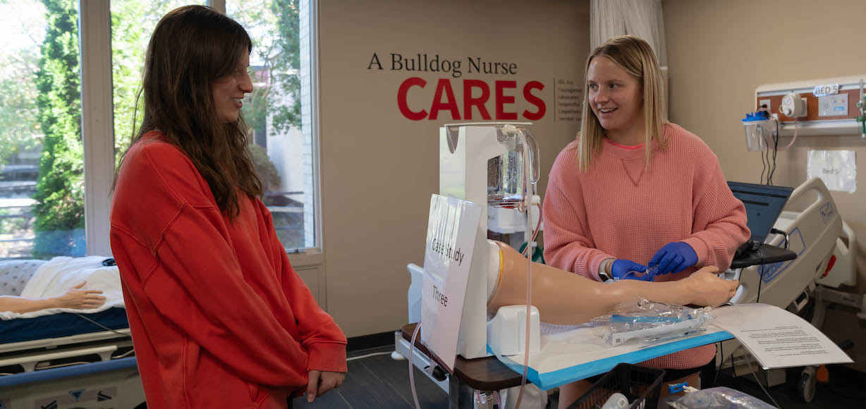 Two nursing students practice on a mannequin in the nursing lab