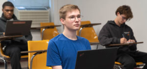 Elijah Lewis sits in a programming class with two other students.