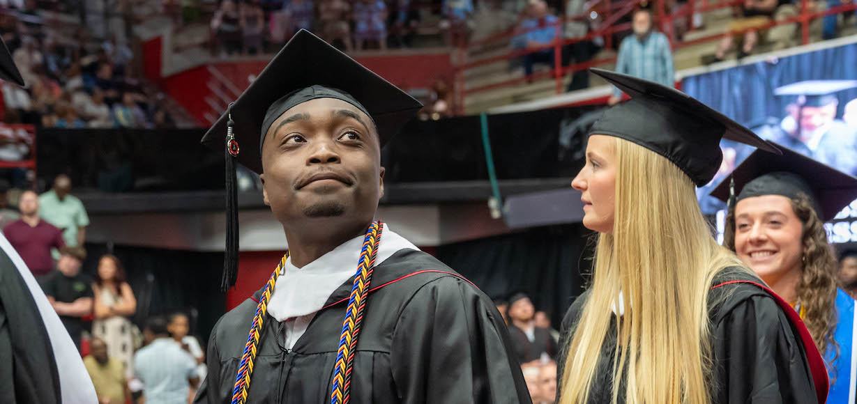 A graduate scans the audience during commencement ceremonies commencement