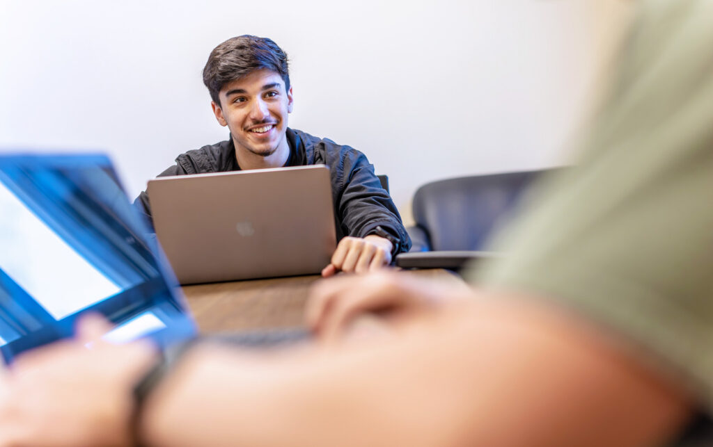Smiling male student on his laptop