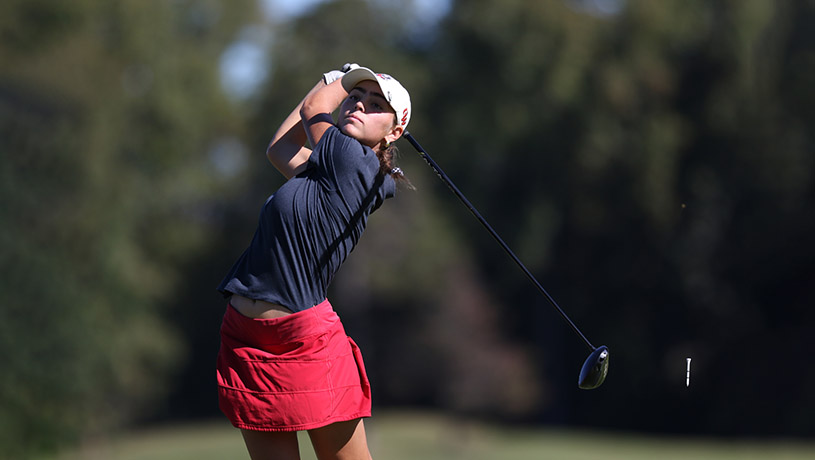 A female student on the golf team hitting a driver.